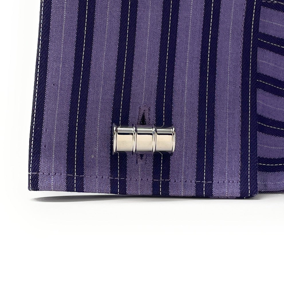 Close-up of a purple striped shirt with a metal button on a white background