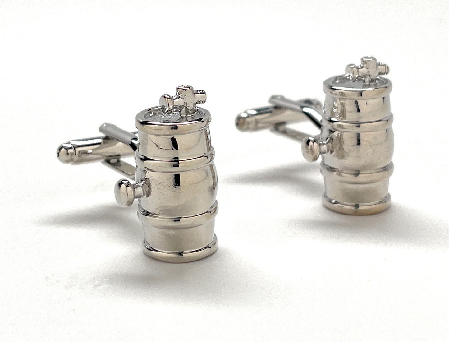 Silver cufflinks shaped like vintage engine starters on a white background