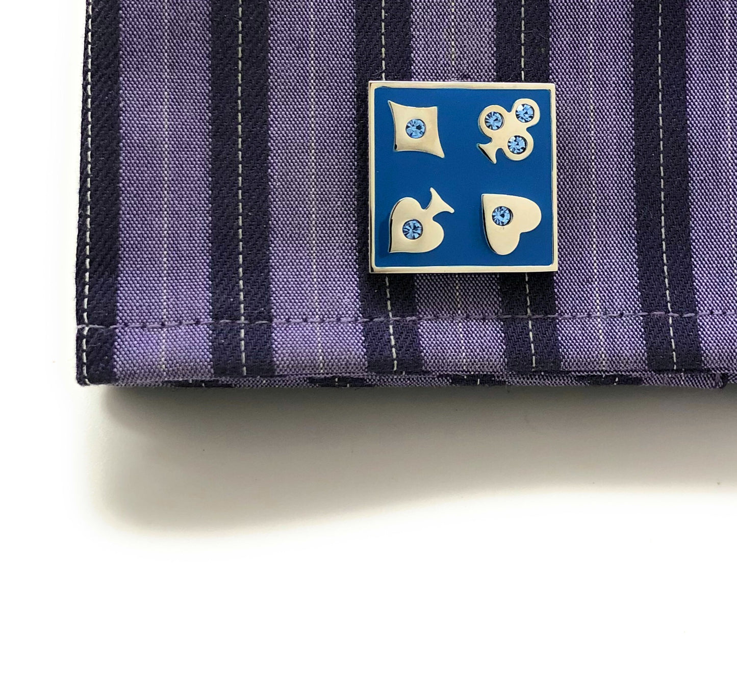 Blue and gold decorative pin on a striped fabric background