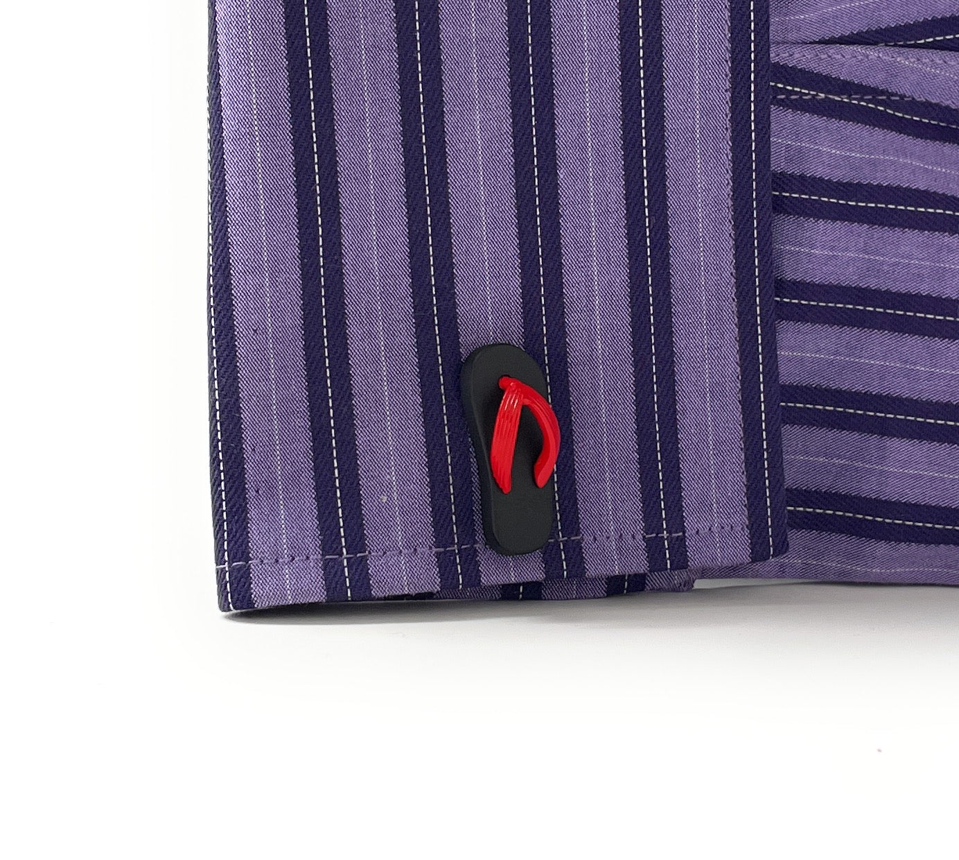 Close-up of a purple striped shirt with a black and red flip-flop design on a white background
