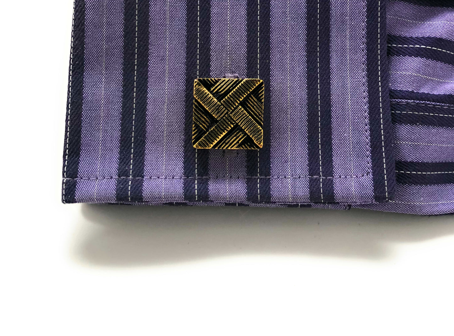 Close-up of a purple and black striped fabric with a gold emblem on a white background