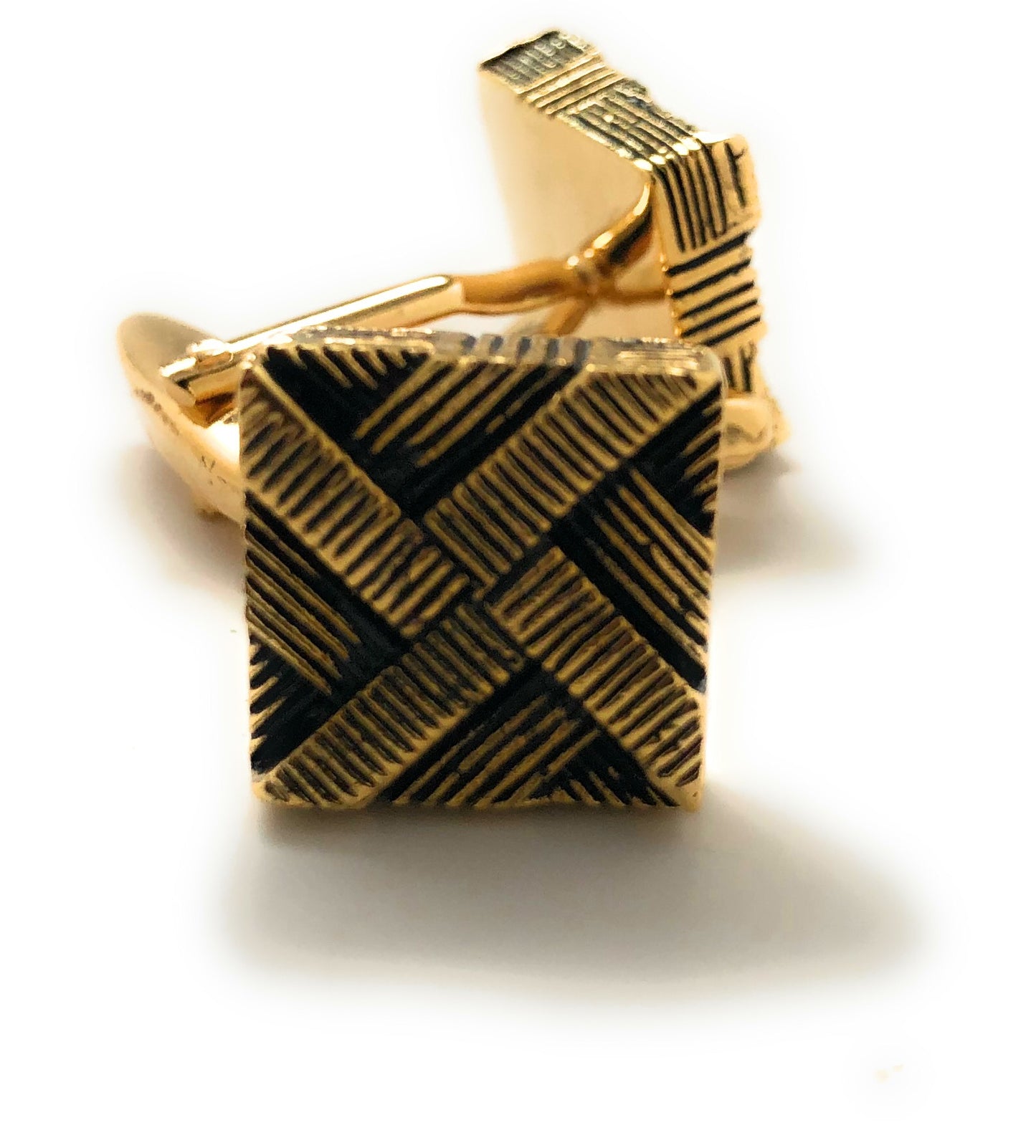 Gold and black patterned cufflinks on a white background
