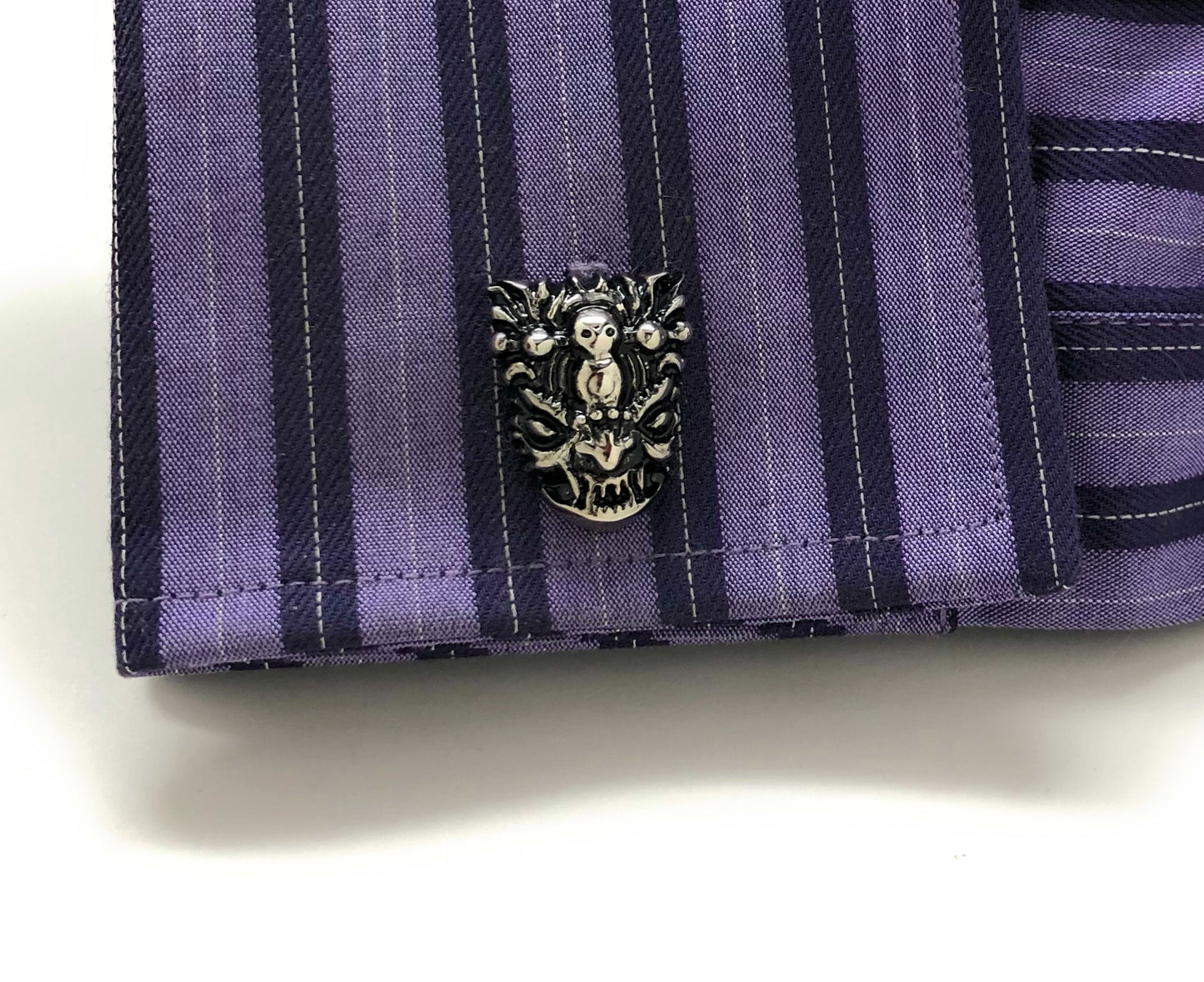 Close-up of a purple striped shirt with a decorative button on a white background