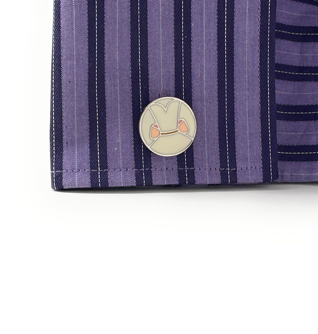 Close-up of a purple striped fabric with a circular emblem featuring a face design.