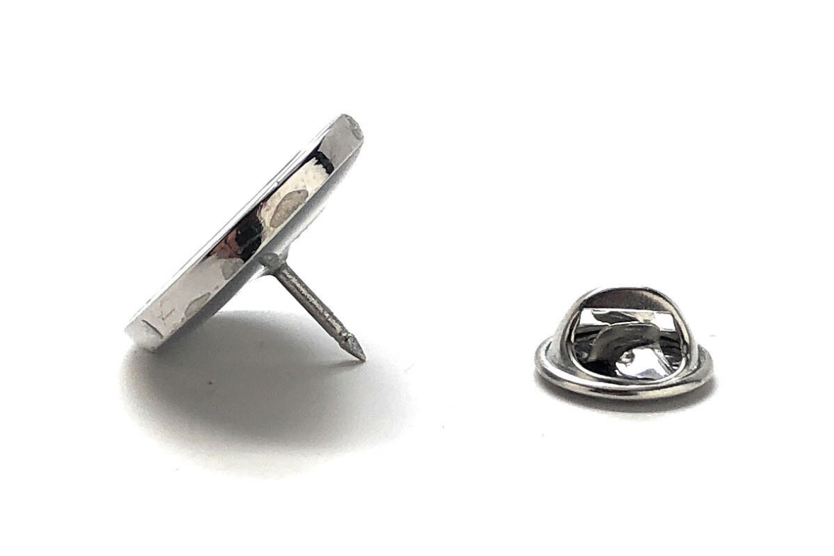A silver and black enamel pin with a James Bond movie poster design, featuring a silhouette of a man in a suit with a cigarette.