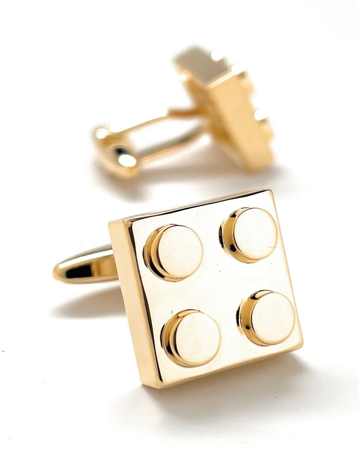Gold cufflinks with a block design on a white background