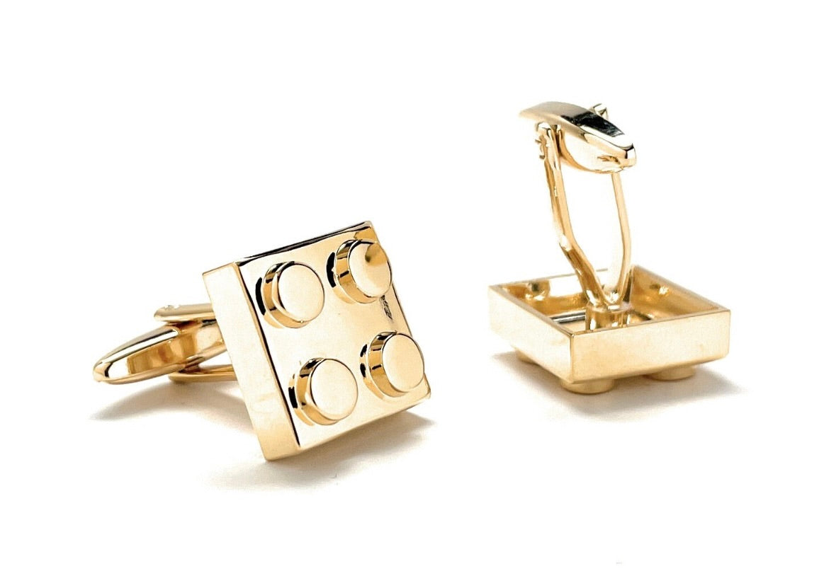 Gold cufflinks designed like building blocks on a white background