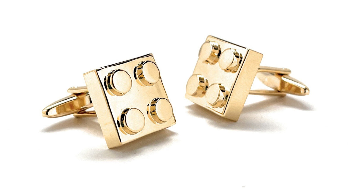 Gold brick-shaped cufflinks on a white background