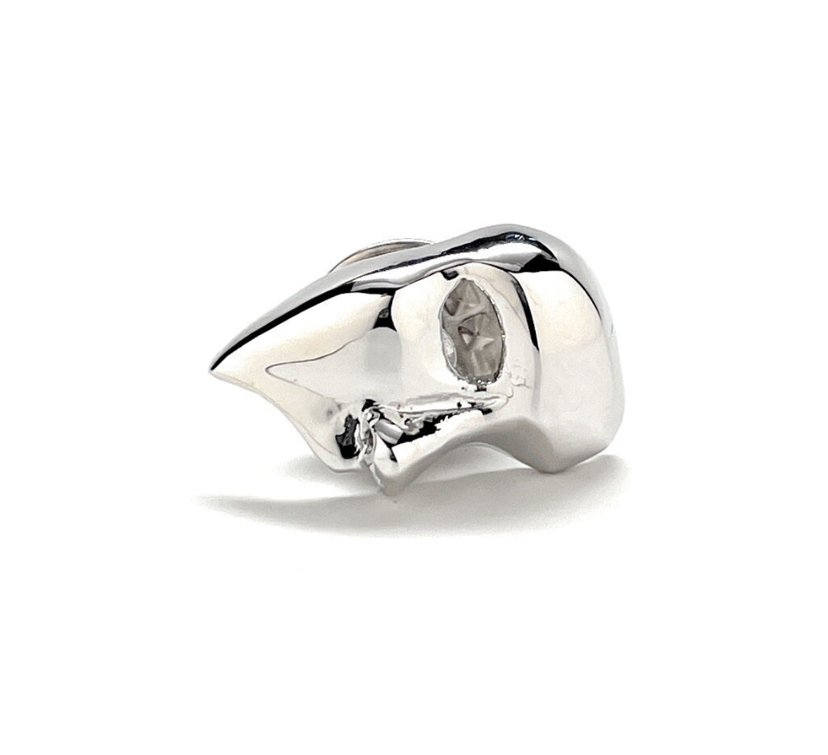 A silver-colored lapel pin in the shape of a mask, with a shiny finish and a butterfly back.
