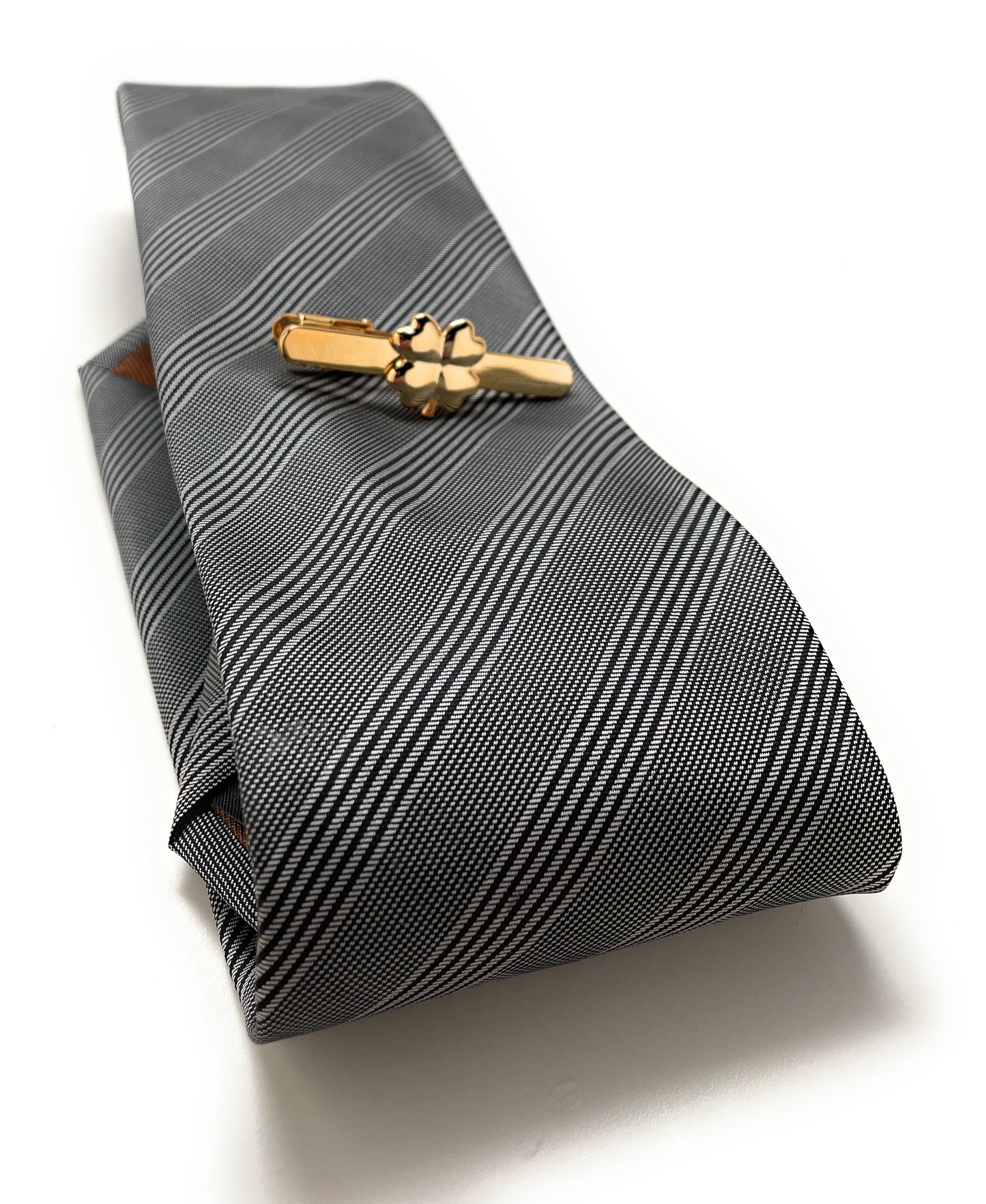 Folded gray striped tie with a gold tie clip on a white background