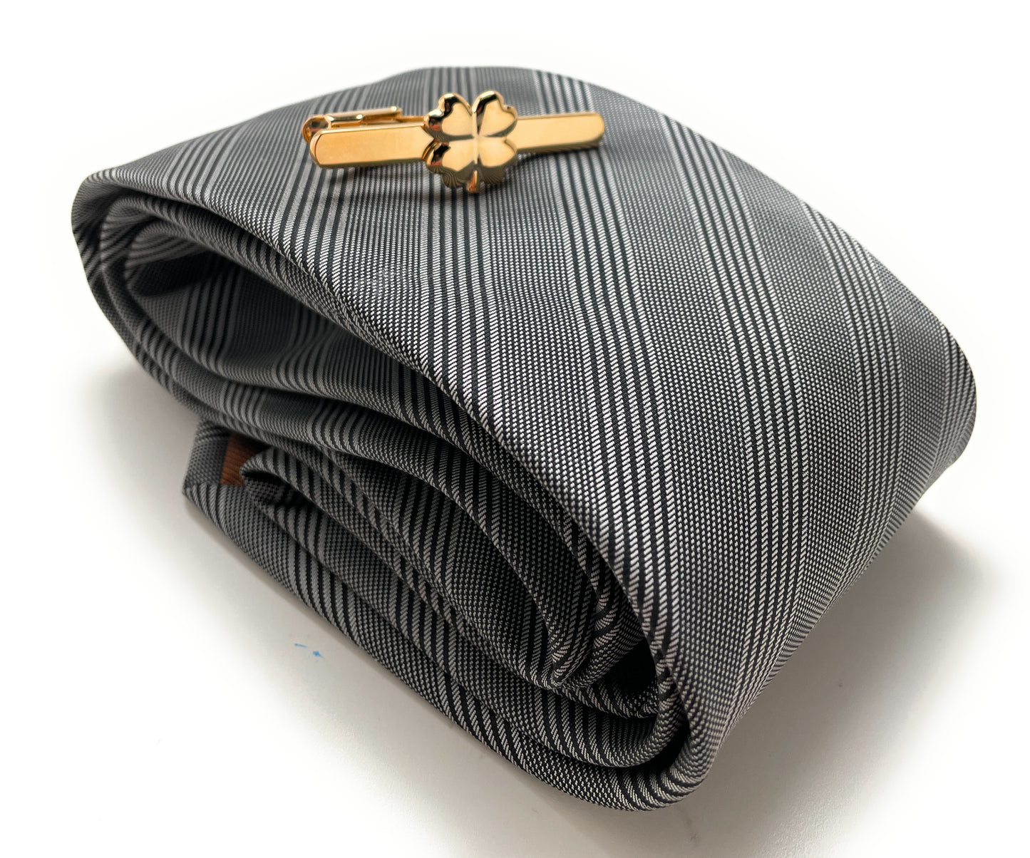 Folded gray tie with a gold tie clip on a white background