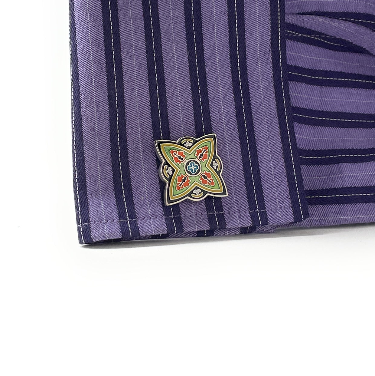 Close-up of a purple striped fabric with a colorful embroidered flower design on a white background