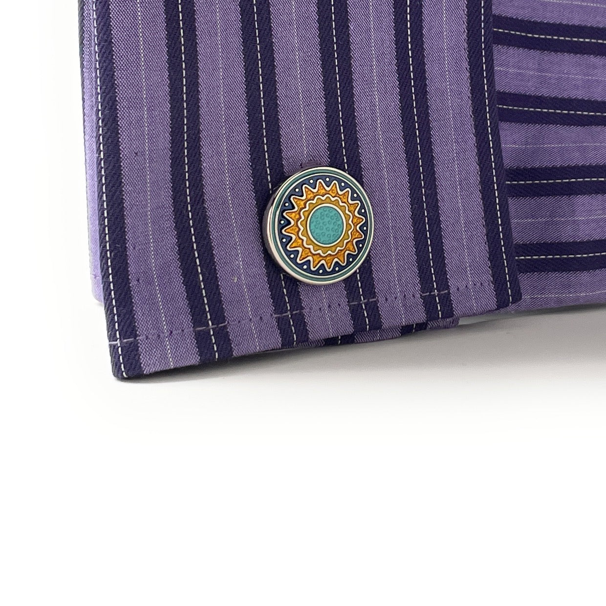Close-up of a purple striped shirt with a decorative button on a white background