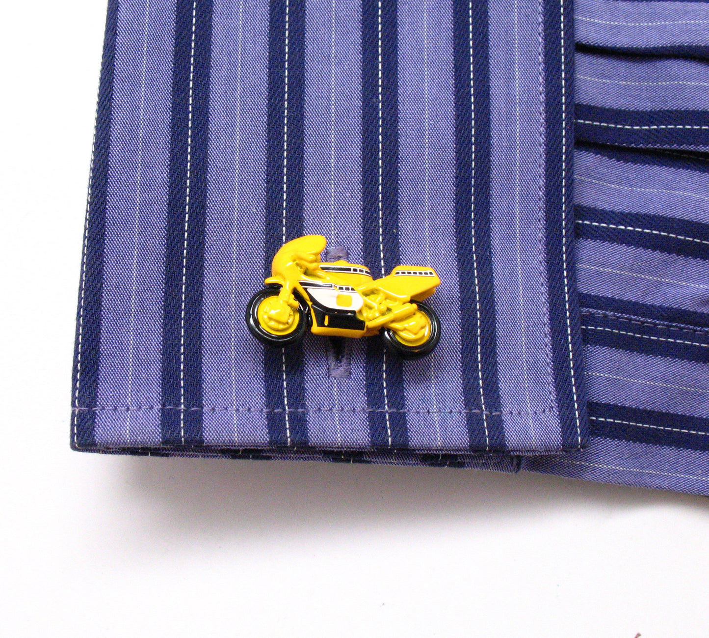 Yellow motorcycle-shaped lapel pin on a blue striped shirt