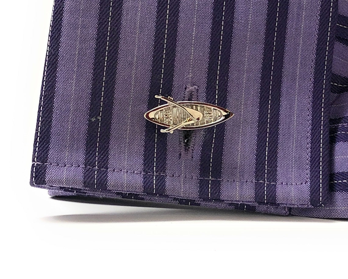Close-up of a purple striped fabric with a gold brooch on a white background