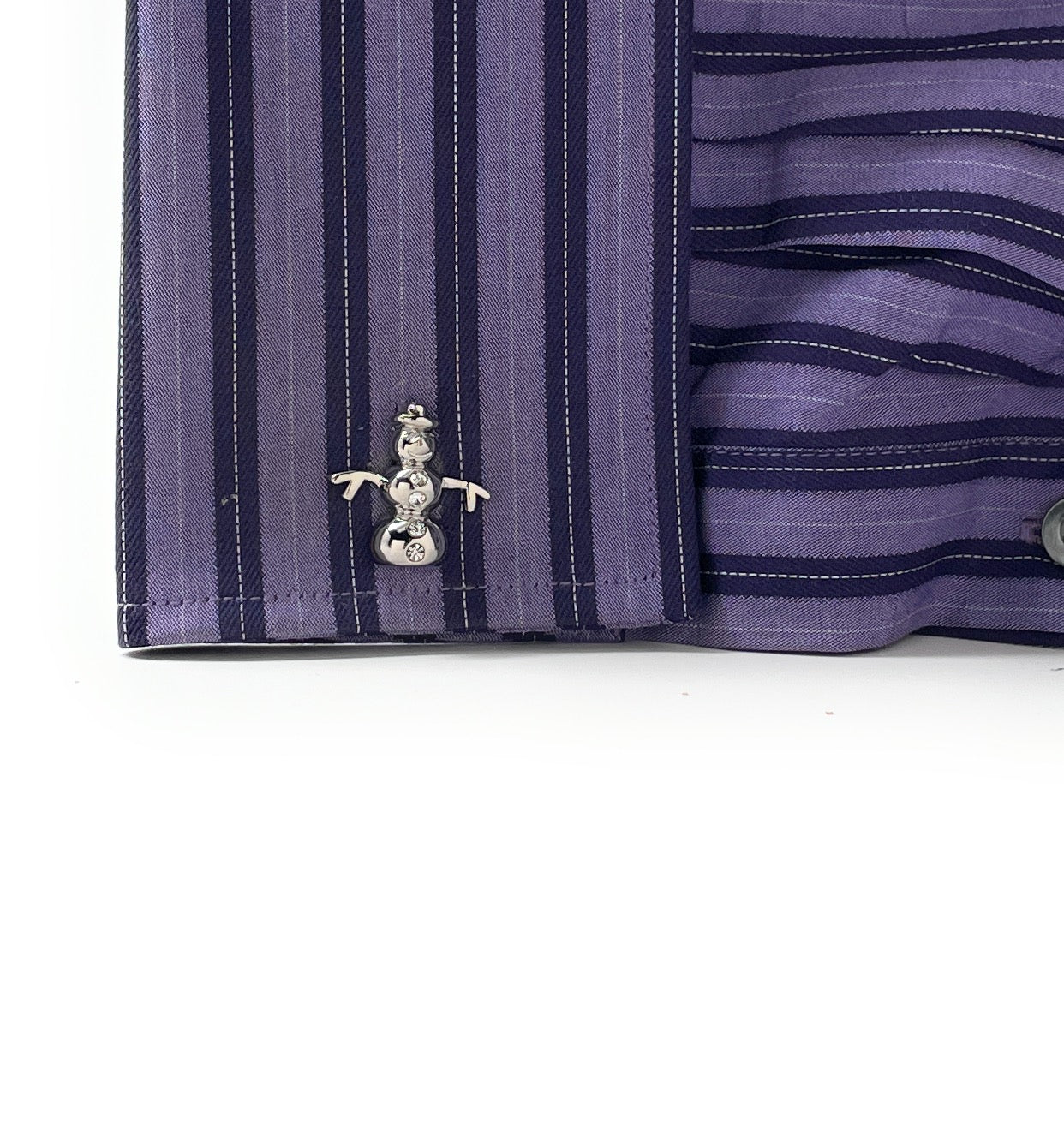 Close-up of a purple striped shirt cuff with a snowman-themed cufflink on a white background