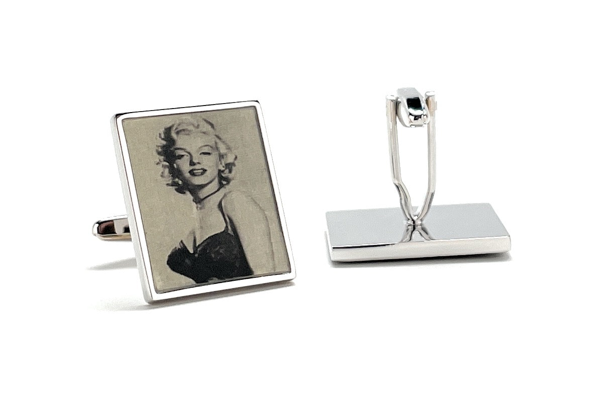 Cufflinks with a portrait of a famous actress on one piece and a plain design on the other, on a white background.