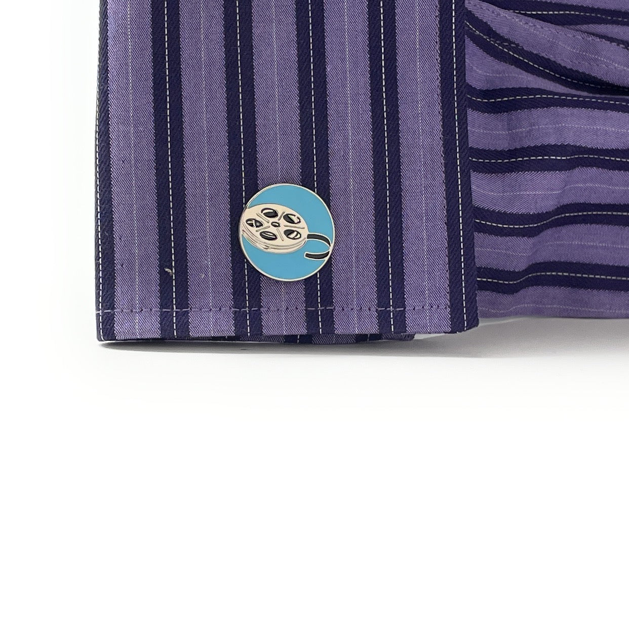 Close-up of a purple striped shirt with a blue and gold button on a white background
