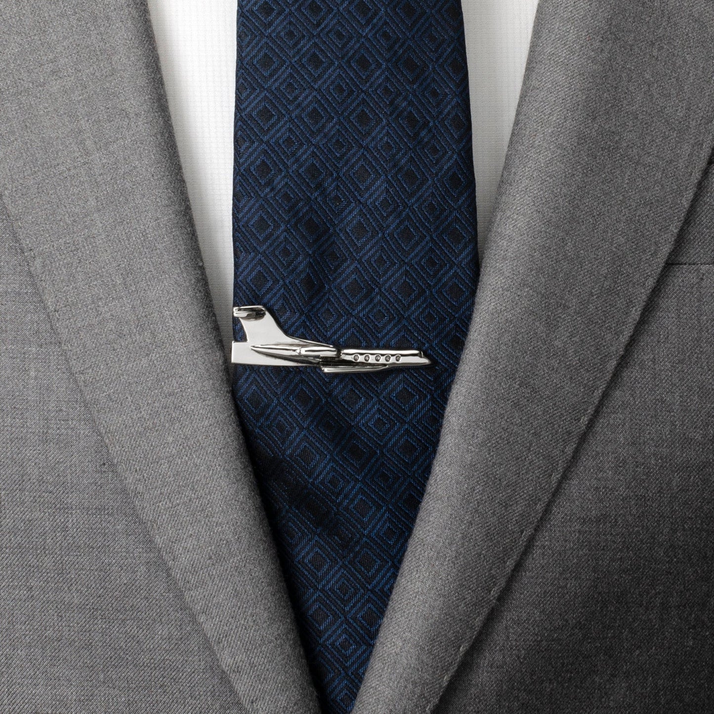 Gray suit jacket with a navy patterned tie and silver tie clip.