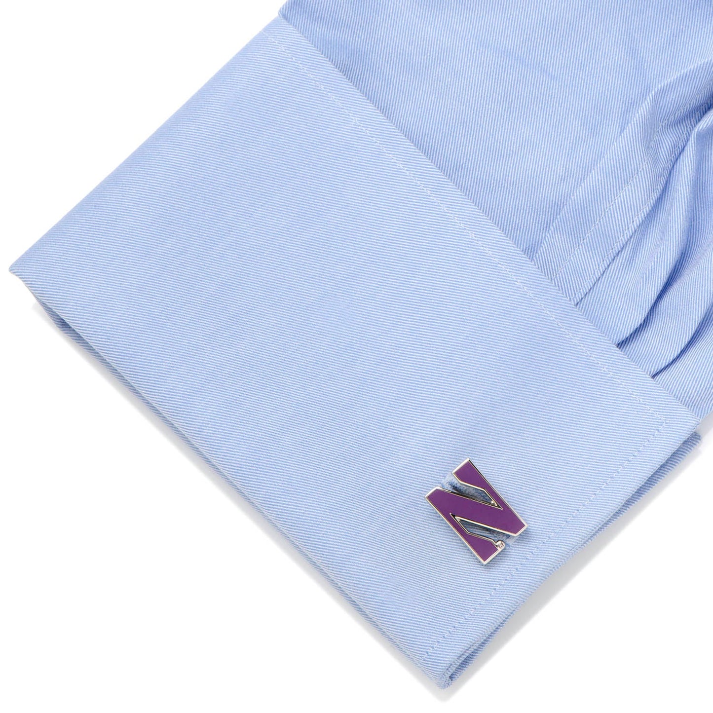 Folded light blue fabric with a purple and gold letter 'N' pin on a white background