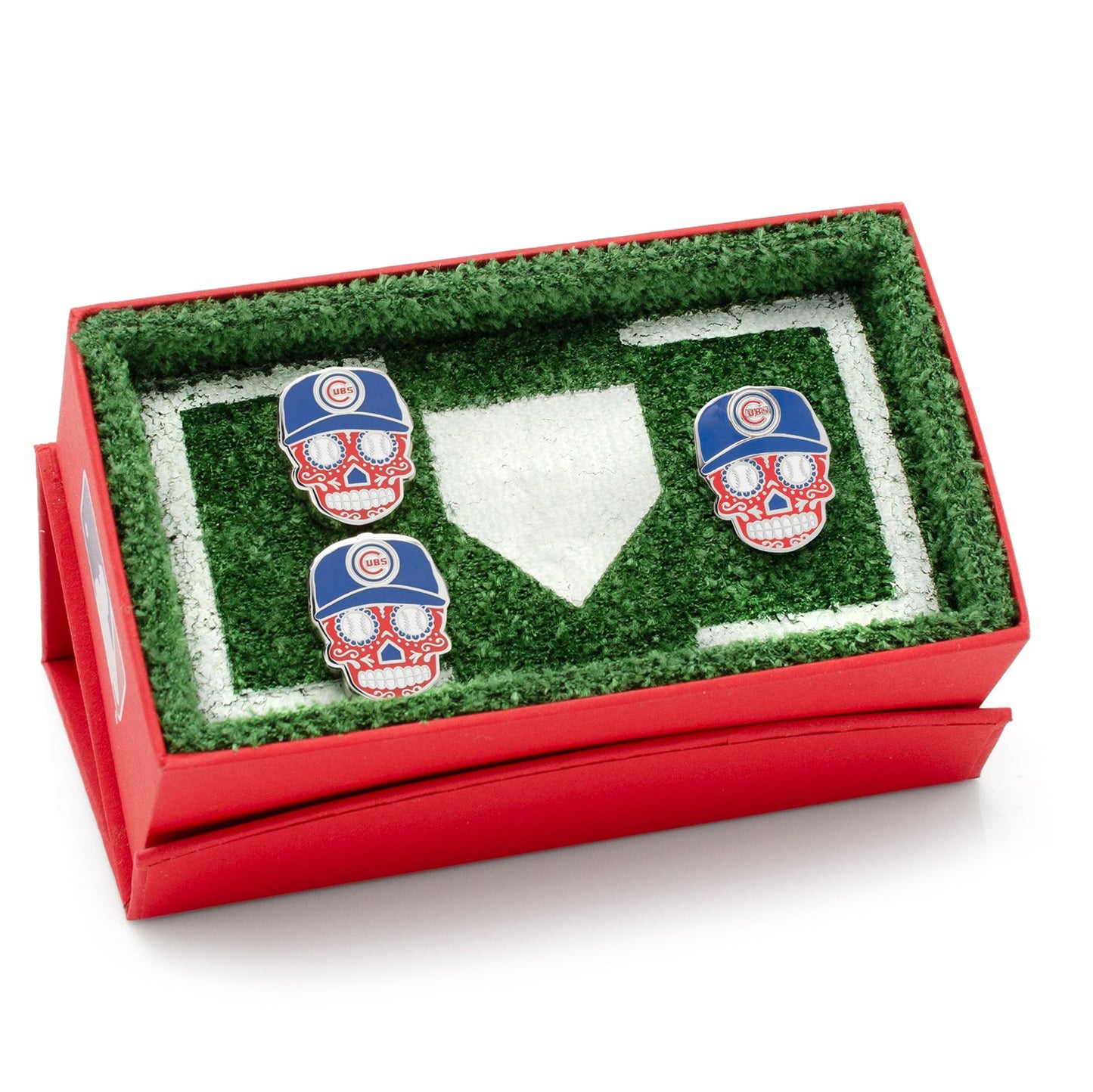 Three skull-shaped earrings with Chicago Cubs hats in a grassy display box.