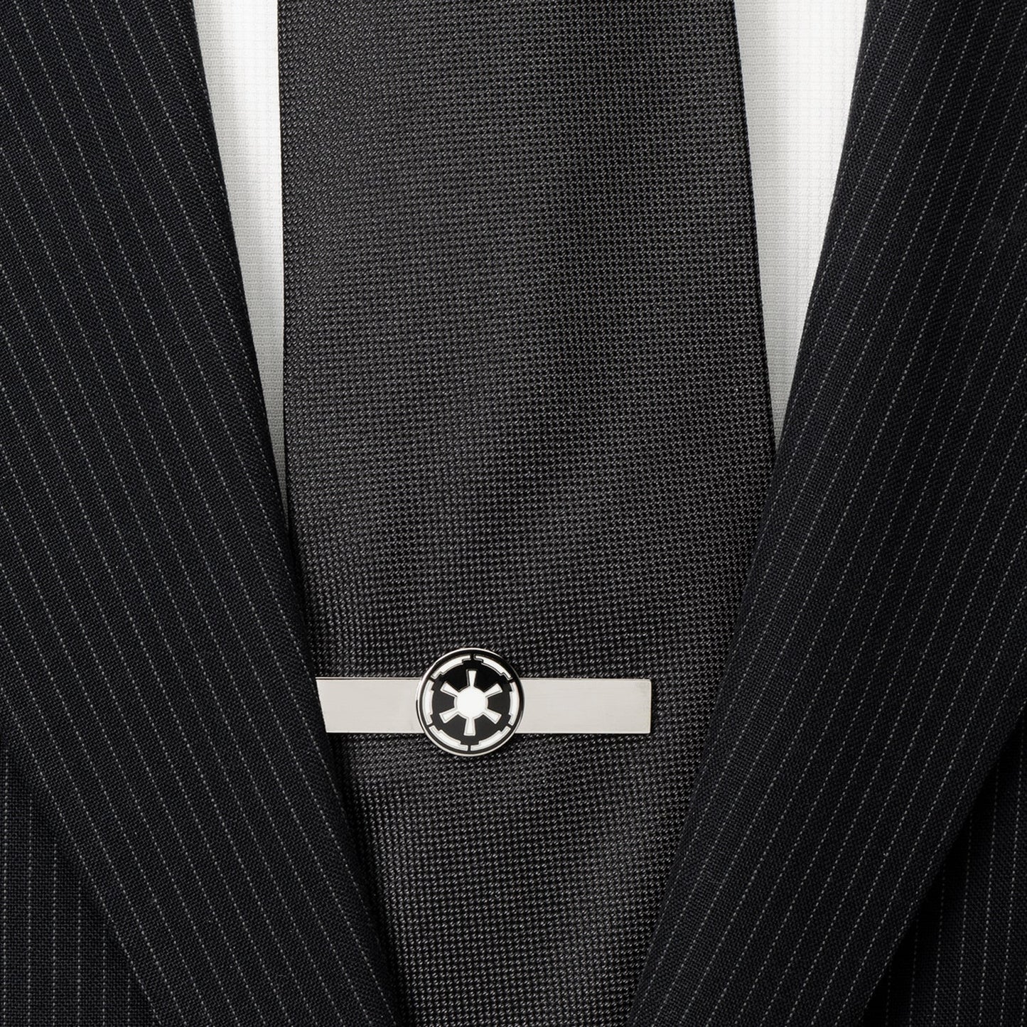 Black tie with a silver tie clip on a black pinstripe suit jacket.