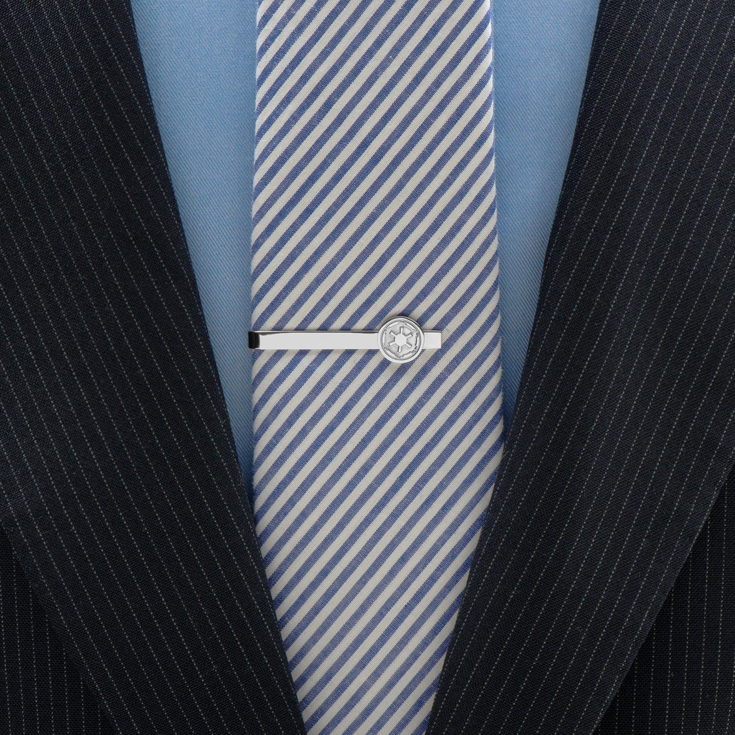 Blue and white striped tie with a silver tie clip on a suit jacket.