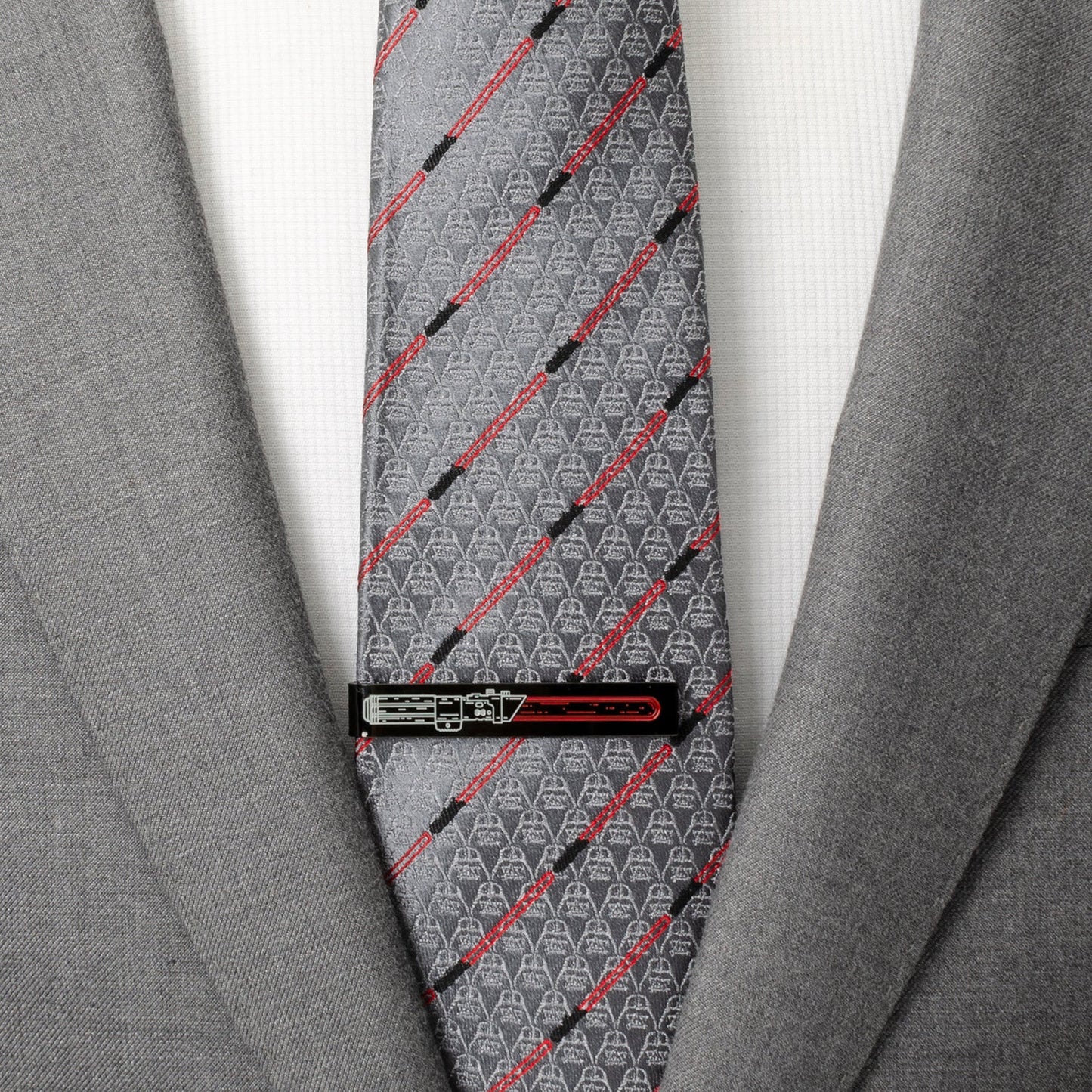 Gray tie with red and black patterns worn with a gray suit jacket.