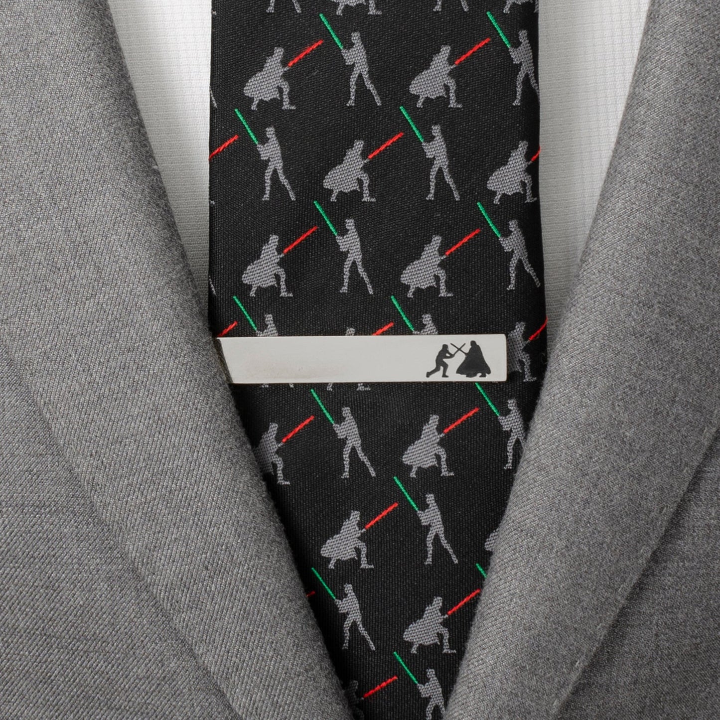 Black tie with light saber pattern and silver tie clip on a gray suit jacket.
