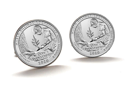 A pair of silver cufflinks featuring an image of a person minting a coin, with a background of a national park.