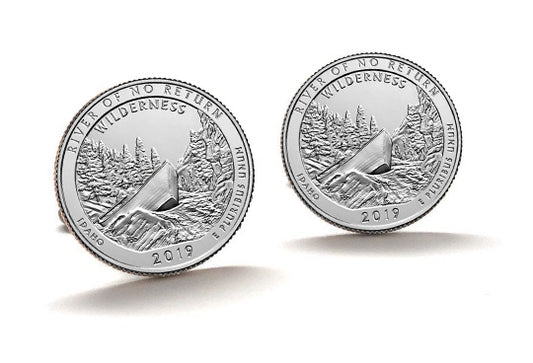 A set of two silver coin cufflinks featuring an image of a wilderness scene with trees and a mountain.