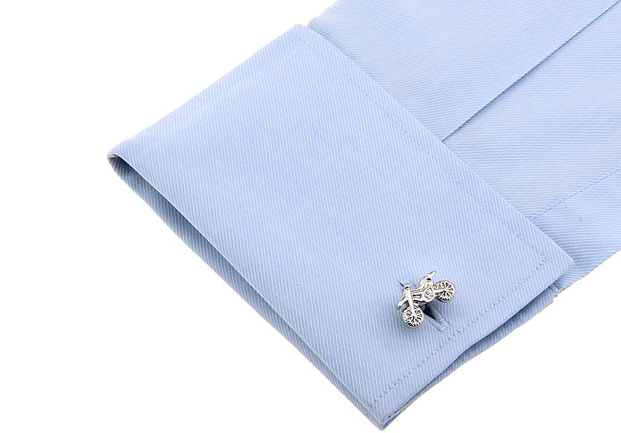 Cufflink on a light blue shirt cuff with a white background
