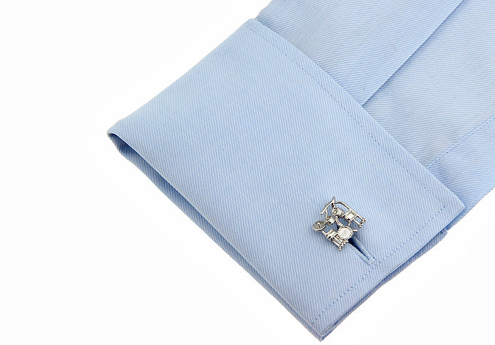 Cufflink on a light blue shirt cuff with a white background