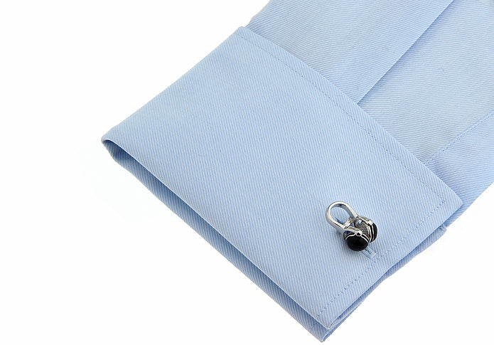 Close-up of a light blue dress shirt cuff with a silver and black cufflink.