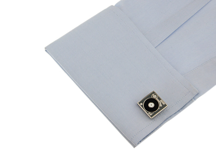 Cufflink on a light blue dress shirt with a white background