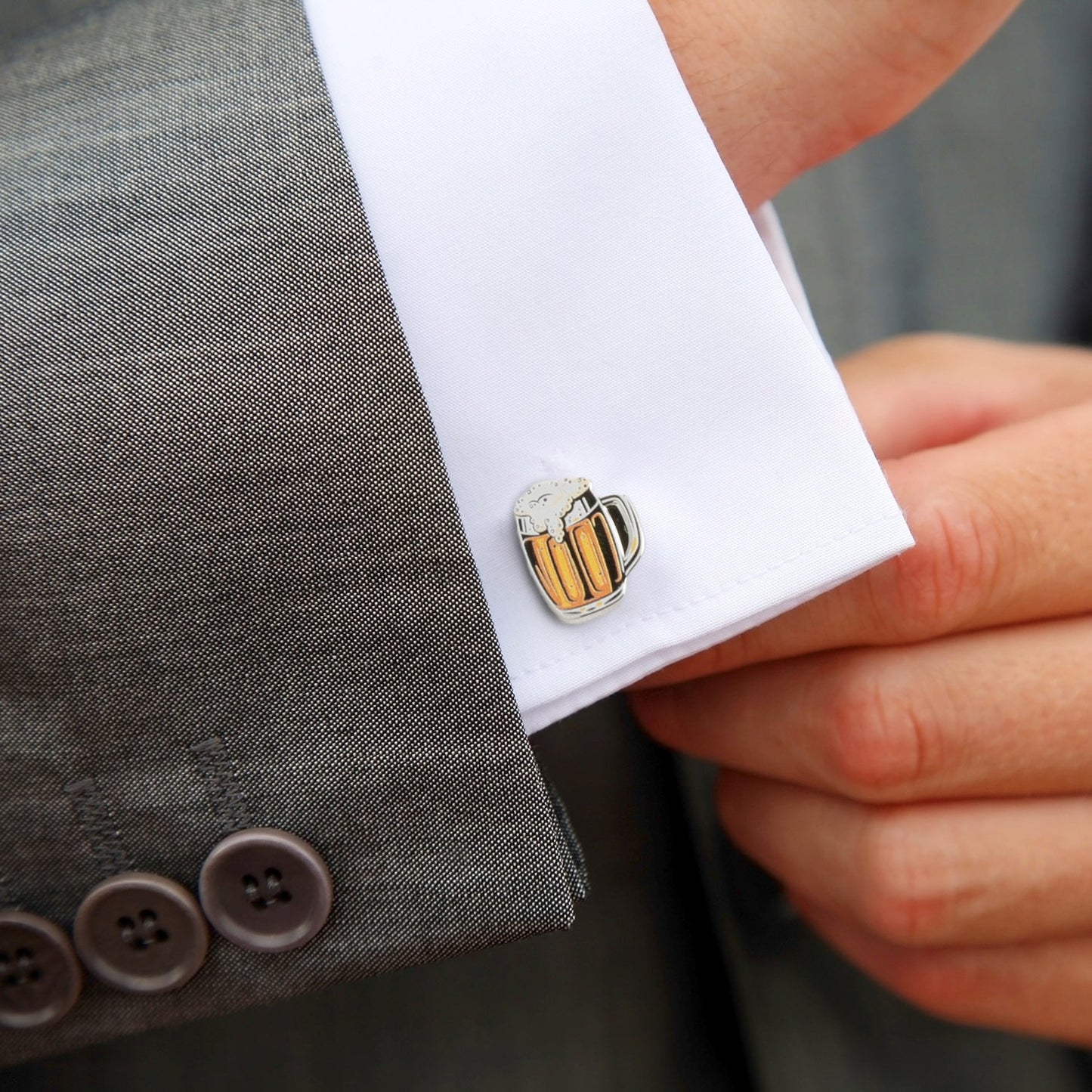 Cufflink shaped like a beer mug on a suit cuff