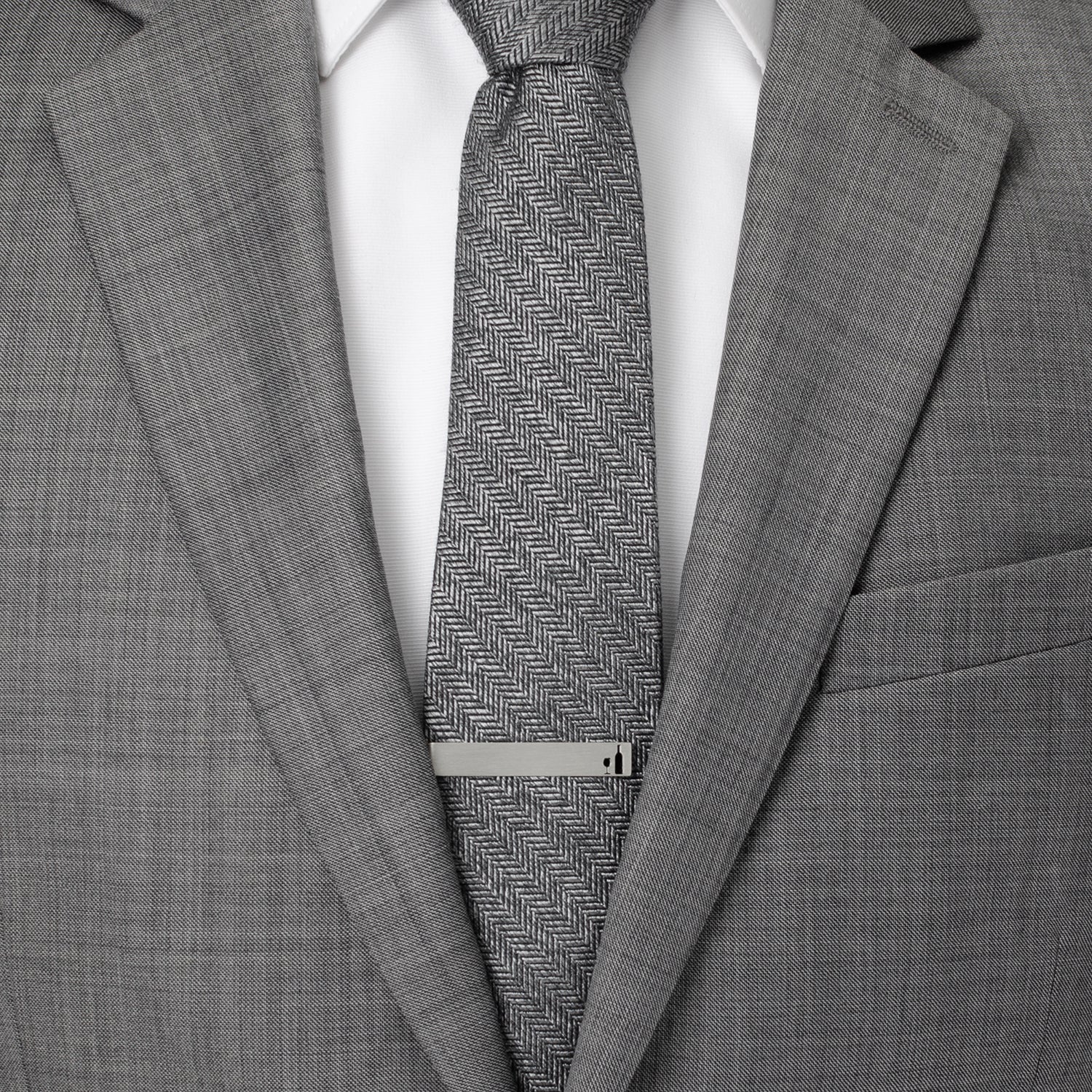 Gray suit with a patterned tie and silver tie clip on a white background