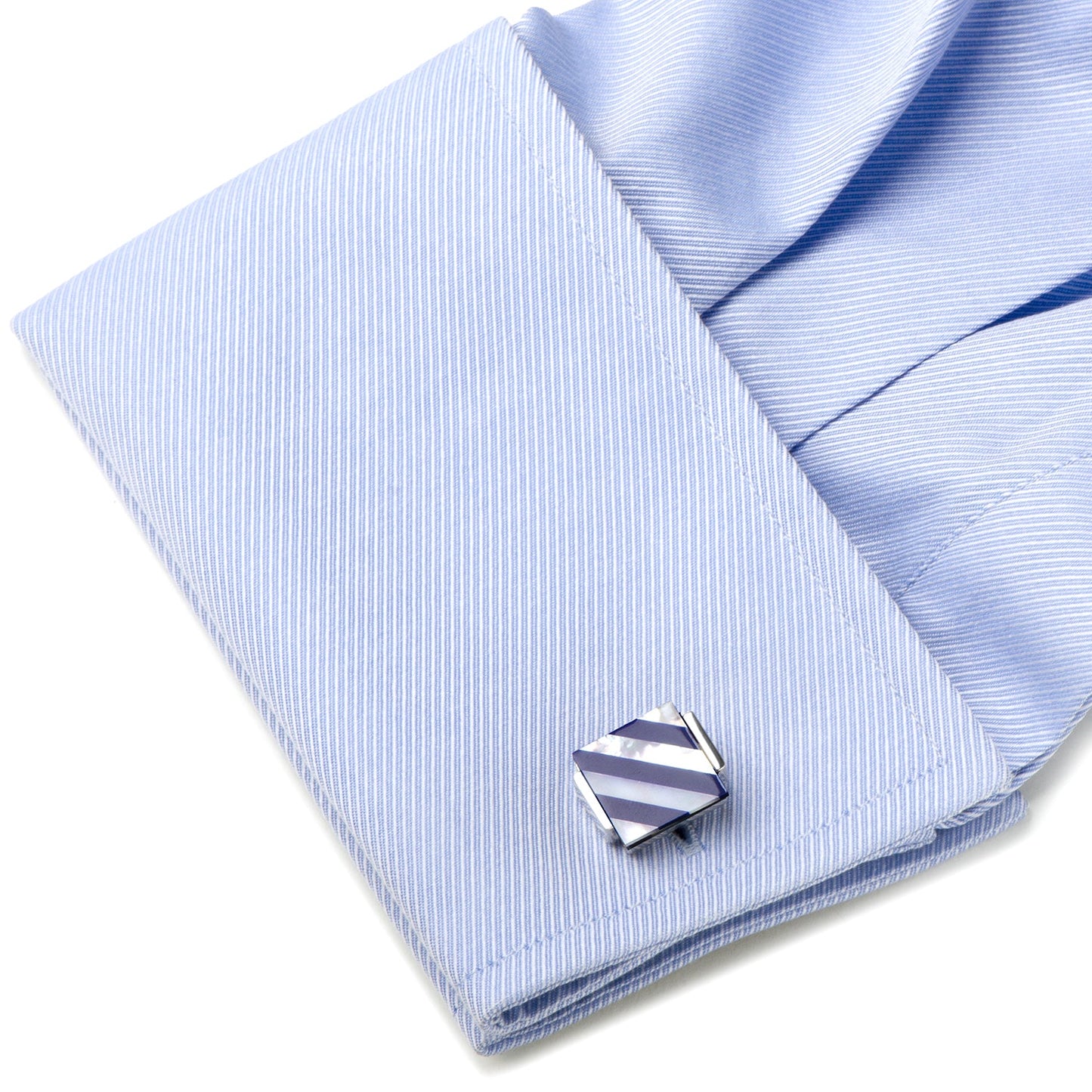 Cufflink on a light blue striped shirt with a white background