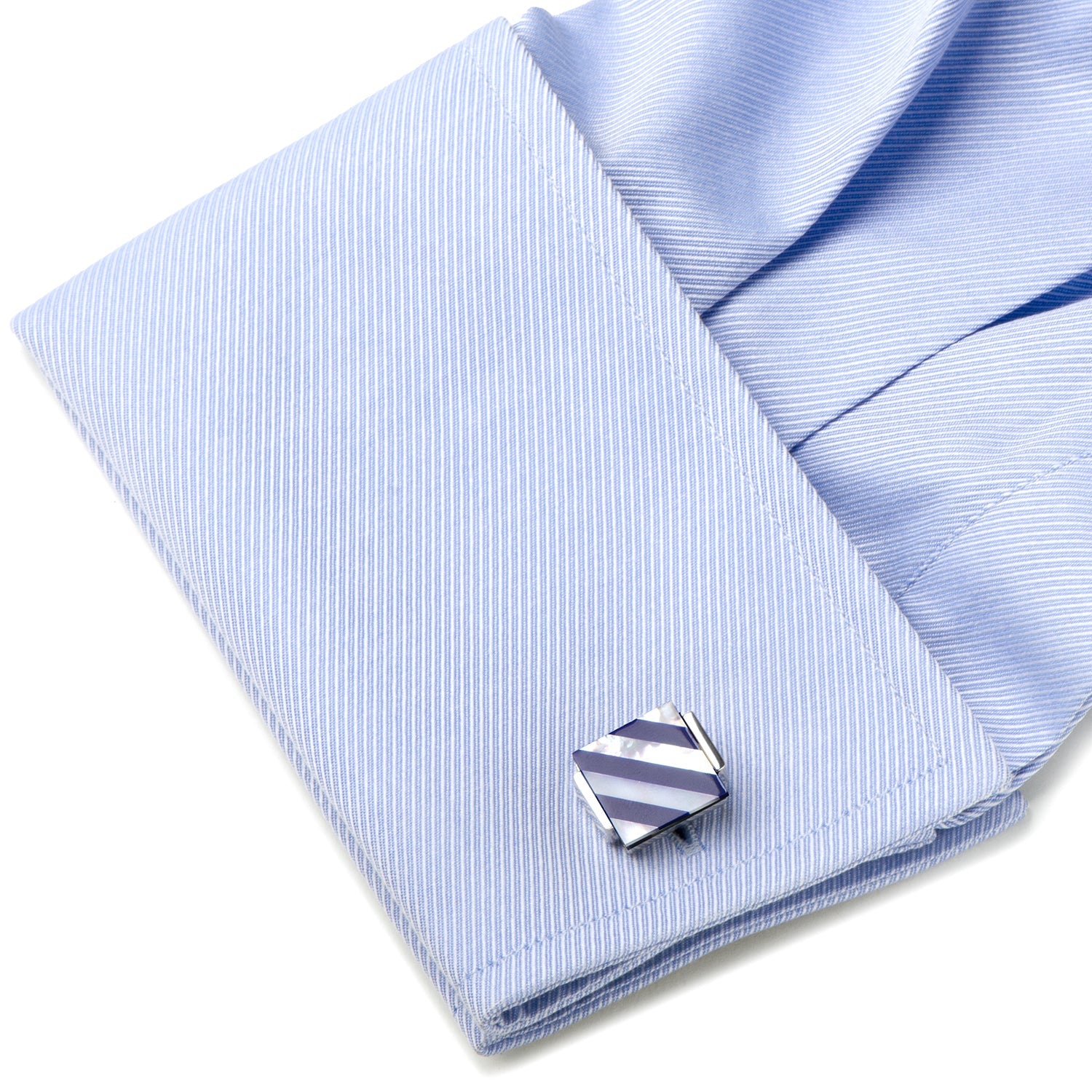 Cufflink on a light blue striped shirt with a white background