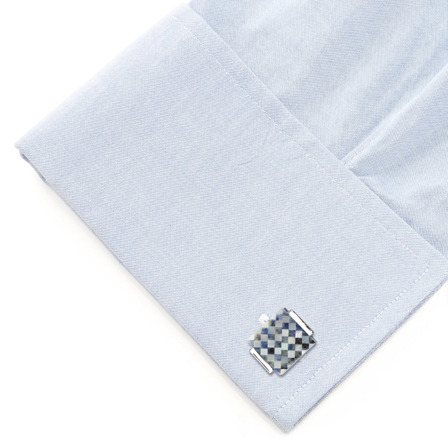 Cufflink on a light blue textured fabric background