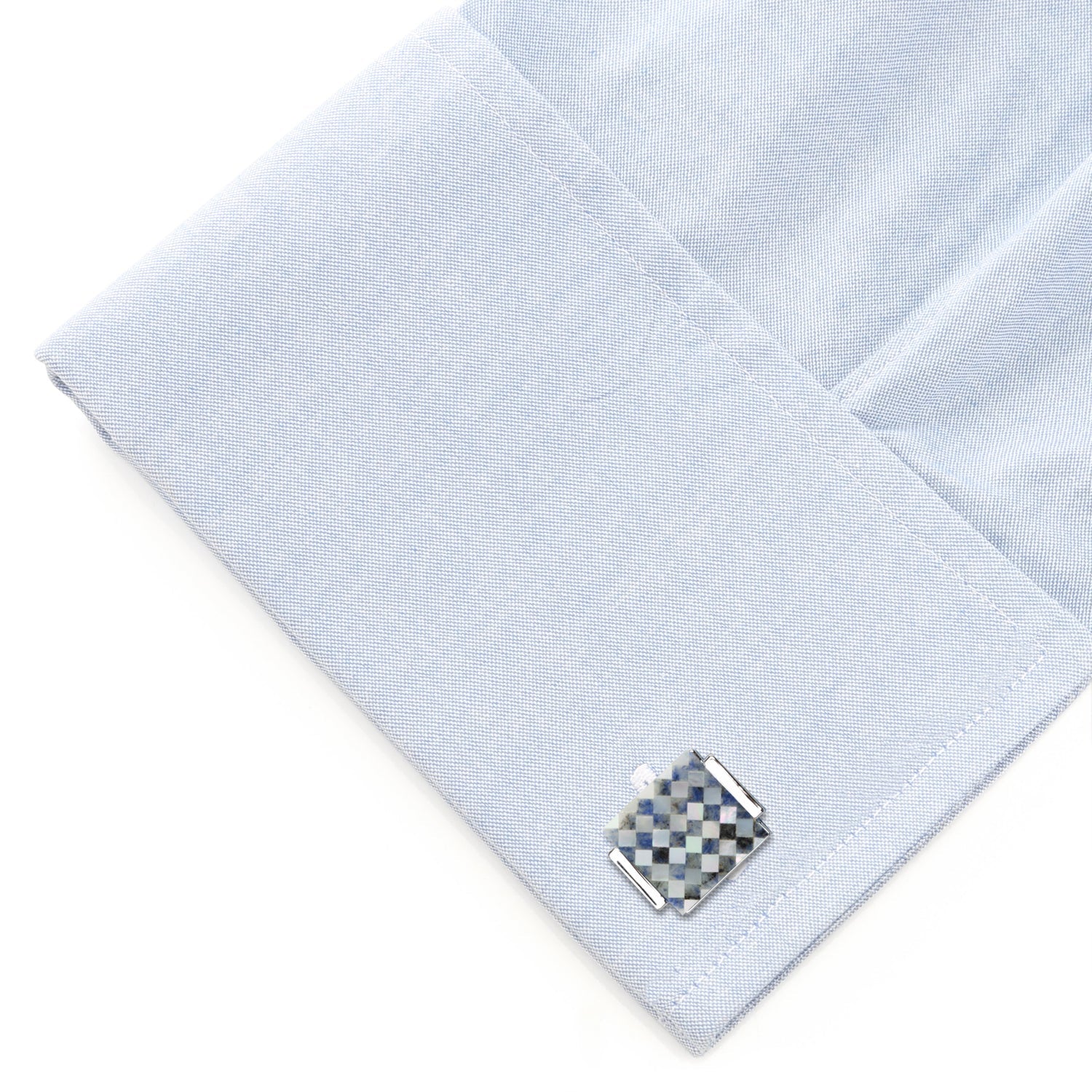 Cufflink on a light blue textured fabric background