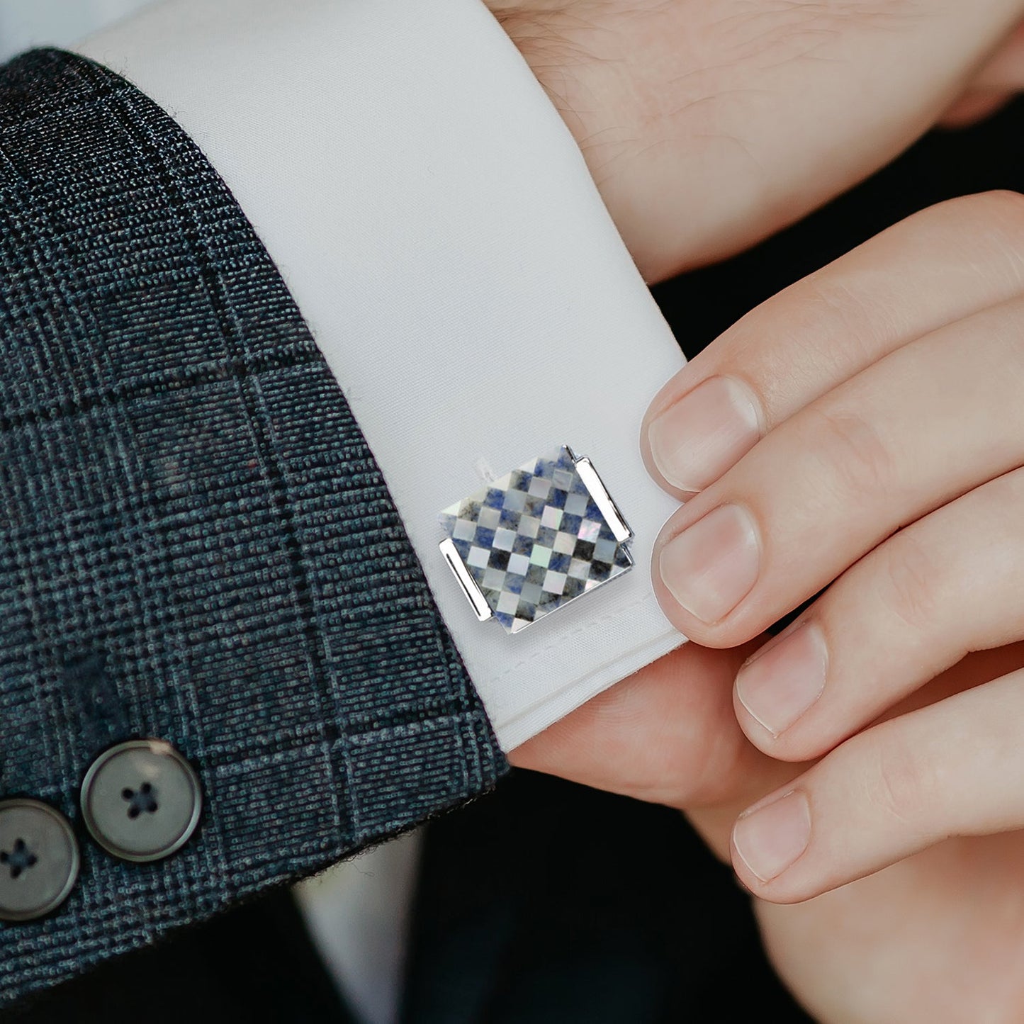 Cufflink on a cuff of a suit jacket with a checkered pattern
