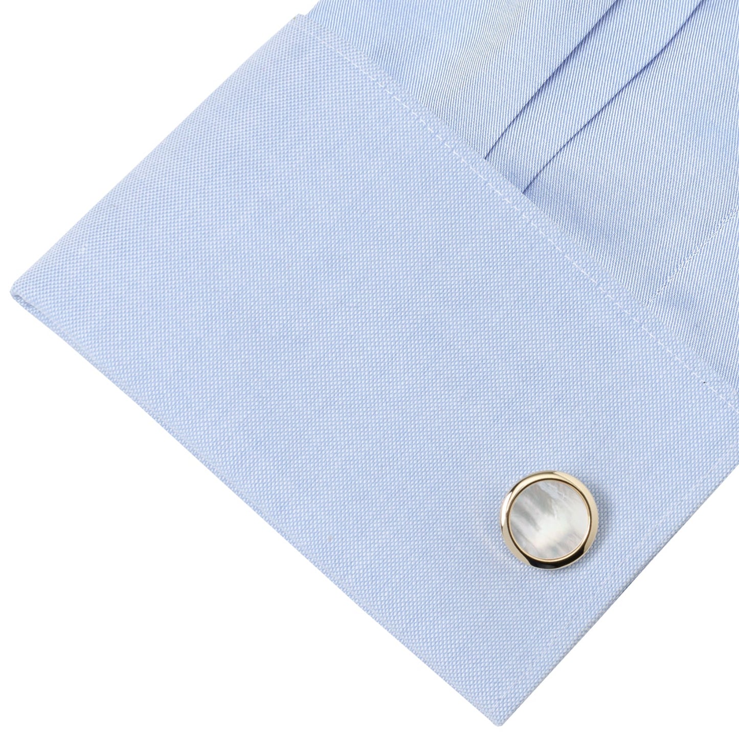 Close-up of a light blue dress shirt with a gold and white cufflink.