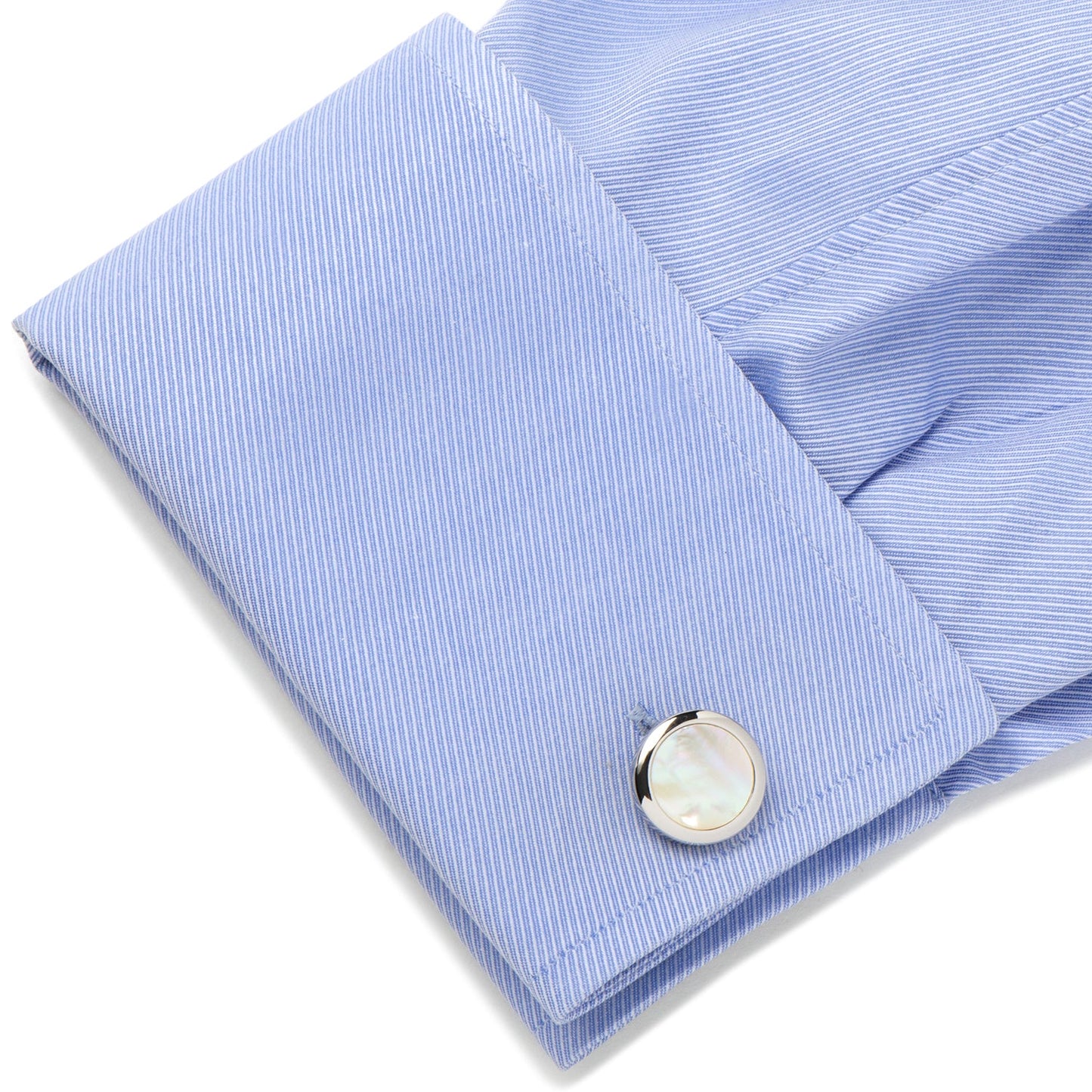 Close-up of a light blue striped shirt cuff with a silver cufflink on a white background
