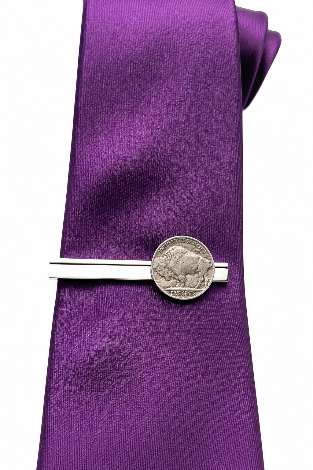 A purple silk necktie with a silver-toned coin tie clip featuring a buffalo coin, set against a plain white background.