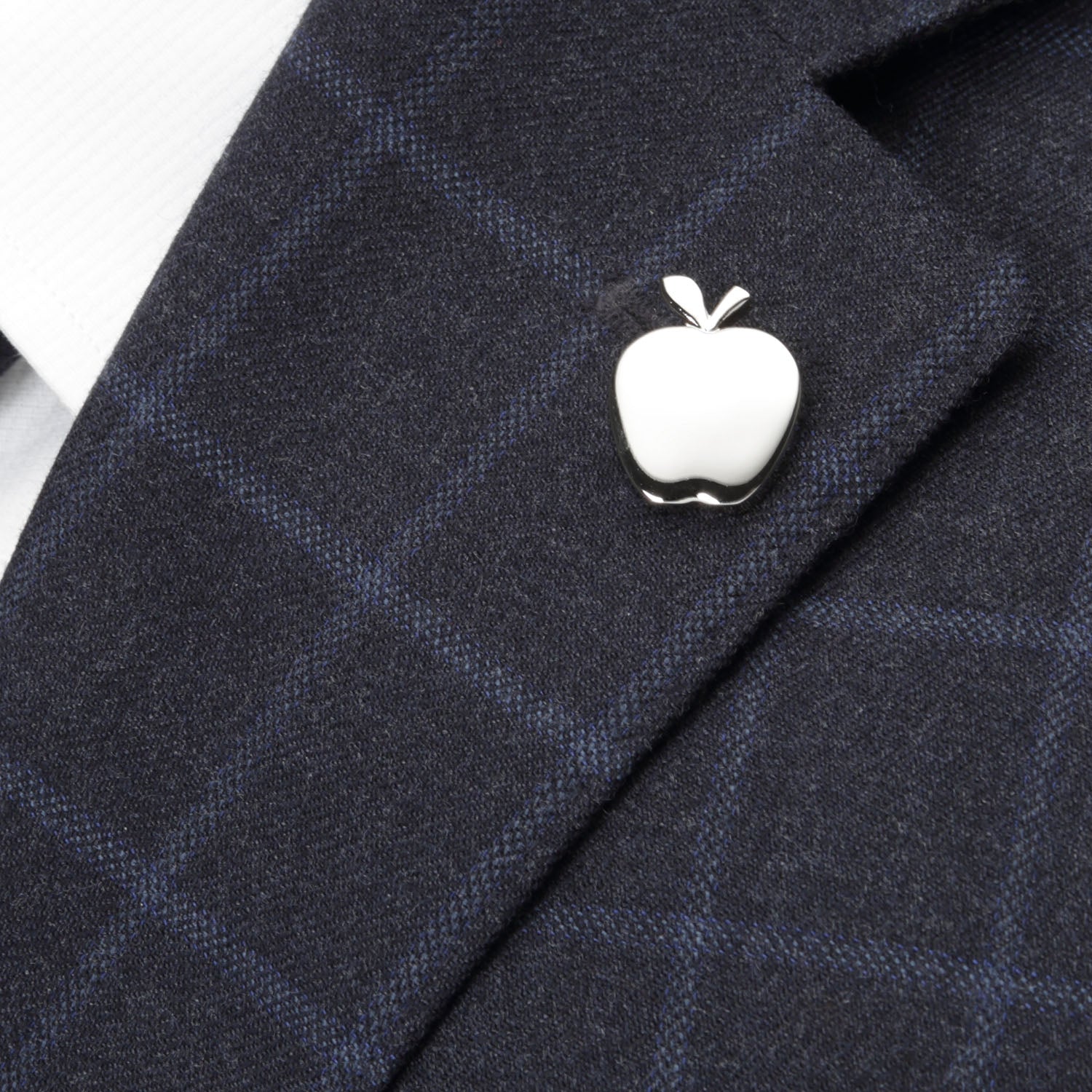 White apple-shaped pin on a dark blue checkered suit jacket