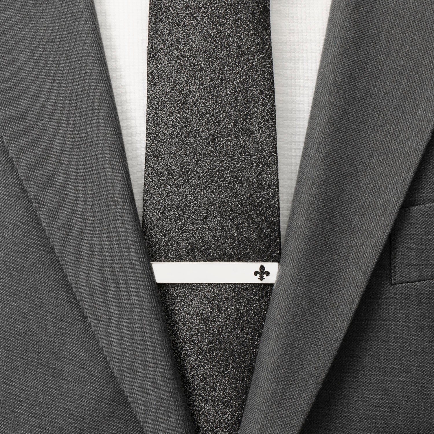 Gray textured tie with a white clasp on a gray suit jacket