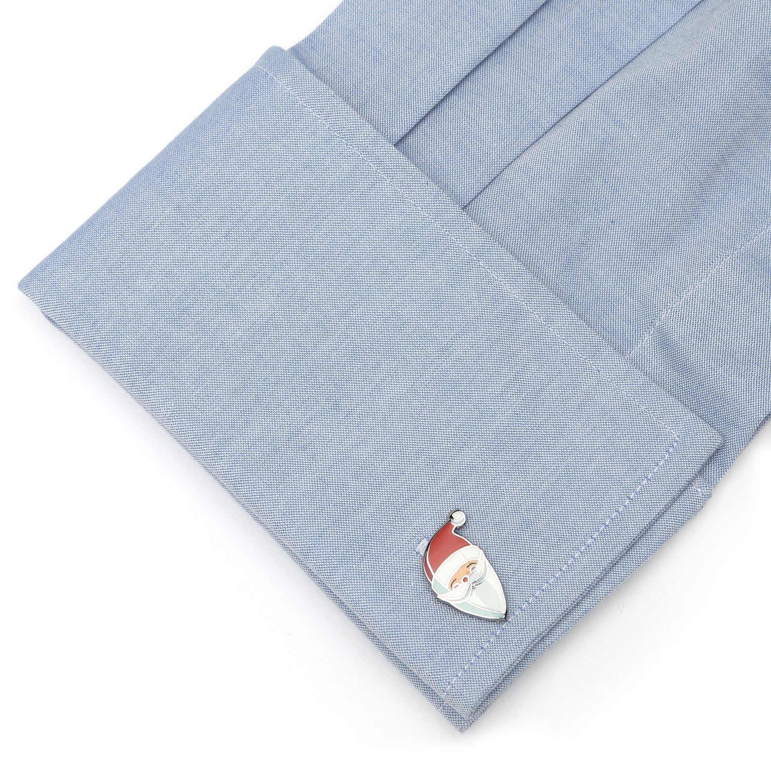 Cufflink with a Santa Claus design on a light blue shirt cuff.