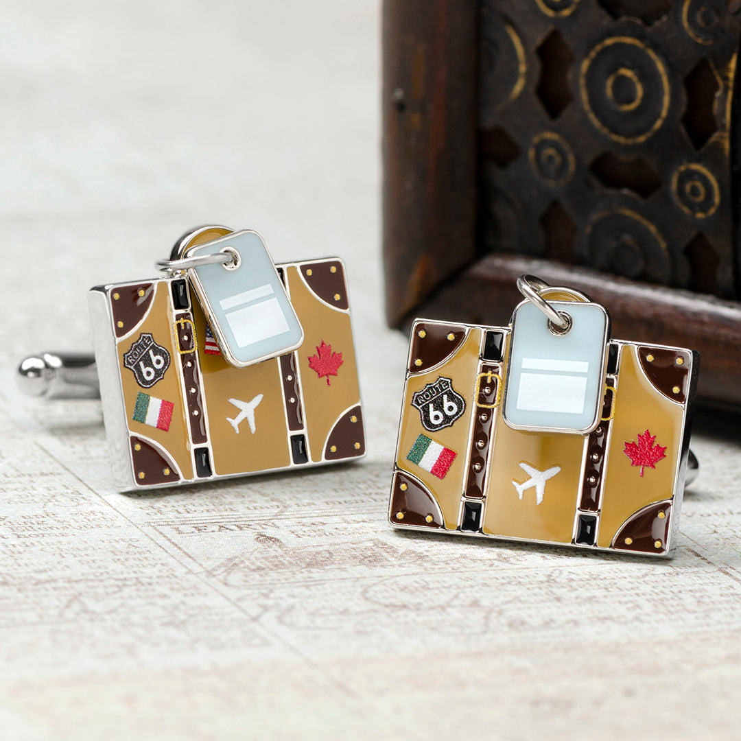 Two luggage-shaped keychains with travel-themed designs on a wooden surface.