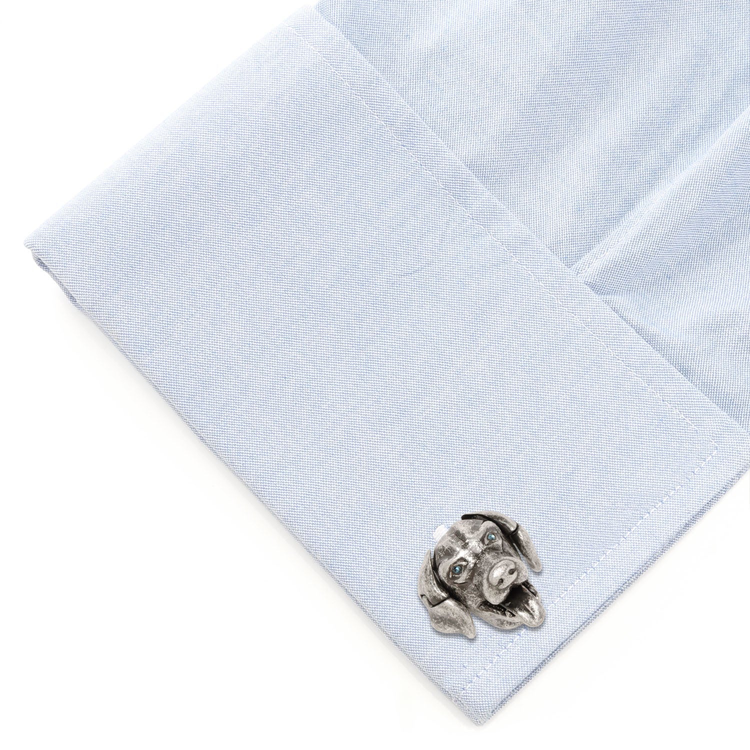 Cufflink on a light blue dress shirt with a white background